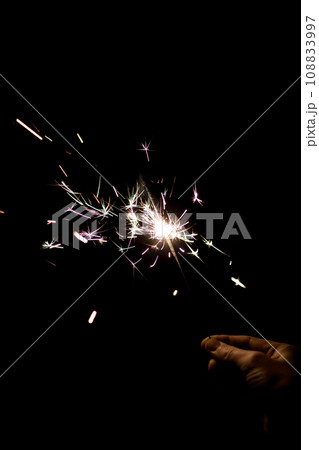 Female hand holding a burning sparkler. 108833997