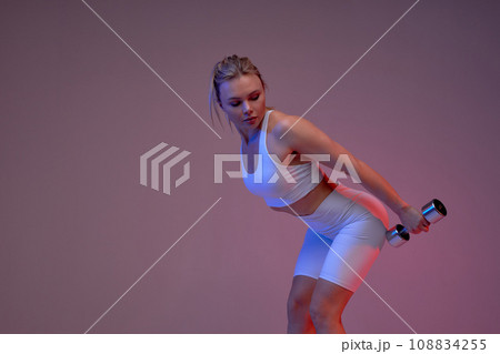 awesome sporty girl bending her back toward, looking back at dumbbells awesome sporty girl bending her back toward, looking back at dumbbells 108834255