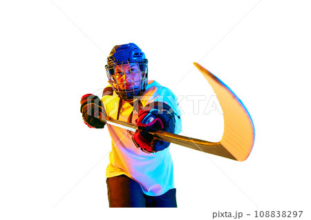 Motivation to win. Young girl, hockey player in helmet and uniform, training, playing against white background in neon light 108838297