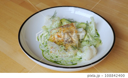 The cook prepares a dish with fish. Close-up professional chef in a restaurant kitchen serving a dish adding the last ingredient by hand. The male chef makes the composition of the dish for serving. 108842400