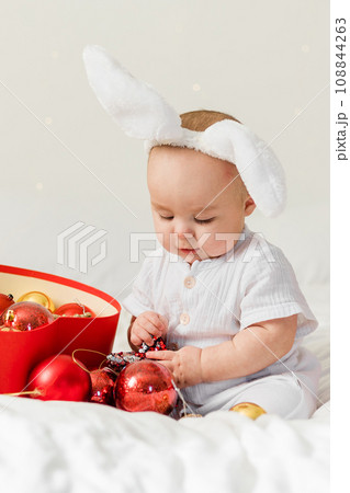 Christmas Baby in Santa Hat Child playing with baubles. Present Gift Box over Holiday Lights background and Merry Christmas concept. Generation alpha and gen alpha Christmas Baby in Santa Hat Child playing with baubles. Present Gift Box over Holiday Lights background and Merry Christmas concept. Generation alpha and gen alpha 108844263