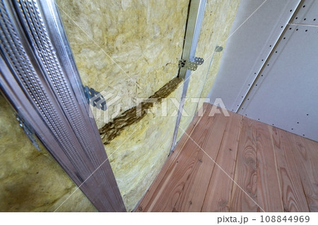 Wall of a room under renovation with mineral rock wool insulation and metal frame prepared for drywall plates. 108844969