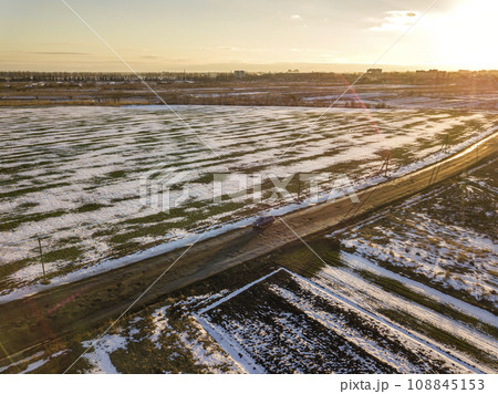 Top view of empty snowy fields patched landscape, dark horizon and bright sky on sunny winter day. Aerial drone photography concept. 108845153
