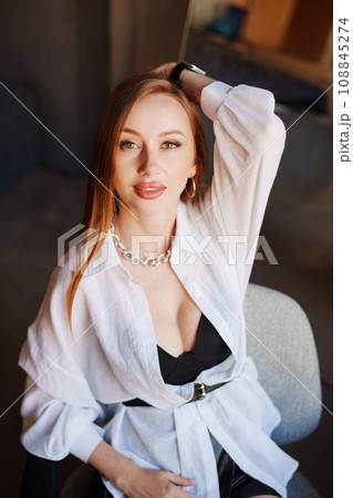 Portrait of sexy redhead young woman in white shirt.  108845274