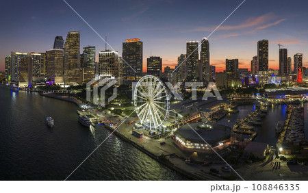 High illuminated skyscrapers of Brickell, city's financial center. Skyviews Miami Observation Wheel at Bayside Marketplace with reflections in Biscayne Bay water and US urban landscape at night High illuminated skyscrapers of Brickell, city's financial center. Skyviews Miami Observation Wheel at Bayside Marketplace with reflections in Biscayne Bay water and US urban landscape at night 108846335
