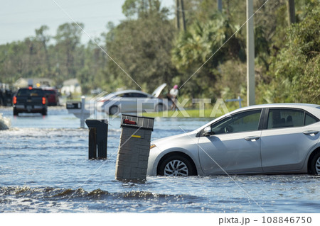 Flooded town street with trapped car submerged under water in Florida residential area after hurricane landfall. Consequences of natural disaster Flooded town street with trapped car submerged under water in Florida residential area after hurricane landfall. Consequences of natural disaster 108846750