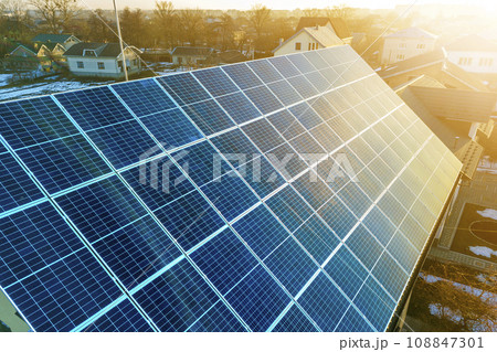 Close-up surface of lit by sun blue shiny solar photo voltaic panels system on building roof. Renewable ecological green energy production concept. Close-up surface of lit by sun blue shiny solar photo voltaic panels system on building roof. Renewable ecological green energy production concept. 108847301