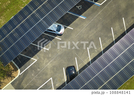 Aerial view of solar panels installed as shade roof over parking lot for parked cars for effective generation of clean electricity. Photovoltaic technology integrated in urban infrastructure Aerial view of solar panels installed as shade roof over parking lot for parked cars for effective generation of clean electricity. Photovoltaic technology integrated in urban infrastructure 108848141