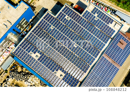 Aerial view of many photo voltaic solar panels mounted of industrial building roof. Aerial view of many photo voltaic solar panels mounted of industrial building roof. 108848212