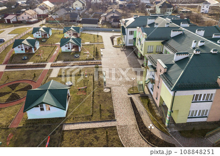 Aerial view of kindergarten or modern school complex, decorated building roofs and colorful playground on sunny yard. 108848251