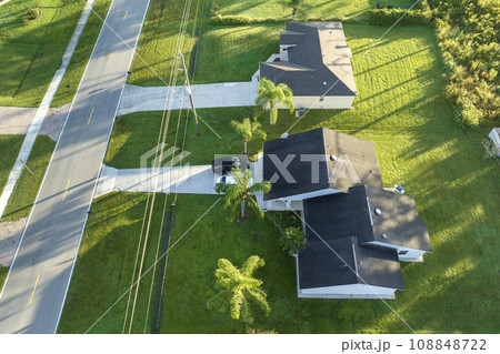Aerial view of american small town in Florida with private homes between green palm trees and suburban streets in quiet residential area Aerial view of american small town in Florida with private homes between green palm trees and suburban streets in quiet residential area 108848722