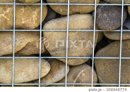 Abstract background of stones behind steel bars 108848774
