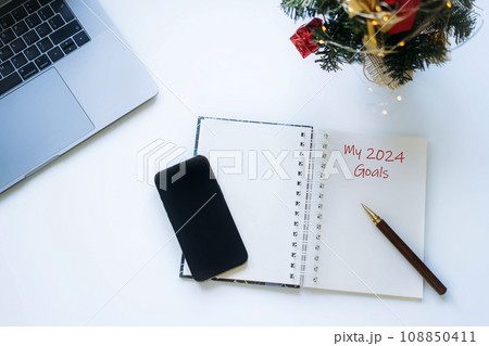 open notepad with Goals for new year text. Laptop and decorated christmas tree nearby open notepad with Goals for new year text. Laptop and decorated christmas tree nearby 108850411