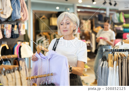 Old woman choosing convenient hoodie in clothing store Old woman choosing convenient hoodie in clothing store 108852125