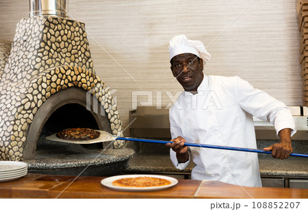 Emotional man chef preparing pizza in pizzeria 108852207