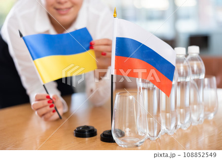 Unrecognizable girl sets midget flags of Russia and Ukraine before international negotiations Unrecognizable girl sets midget flags of Russia and Ukraine before international negotiations 108852549