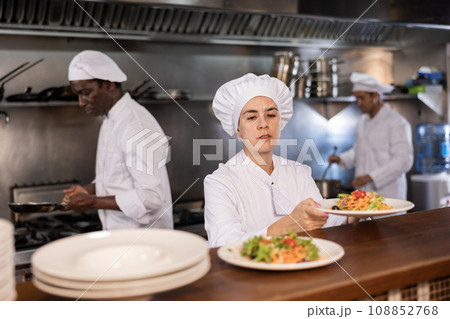 Female chef puts meals on shelves in restaurant 108852768