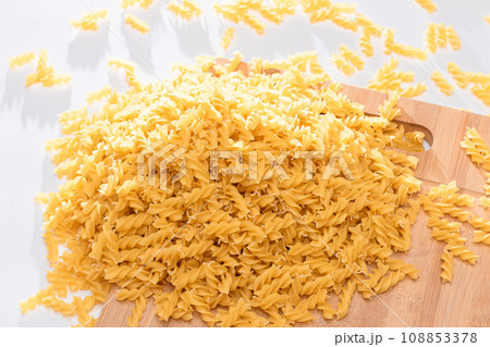 Uncooked Fusilli Pasta Scattered on Wooden Board 108853378
