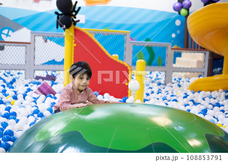 Little Asian boy looking at a floating ball Among many small balls Little Asian boy looking at a floating ball Among many small balls 108853791