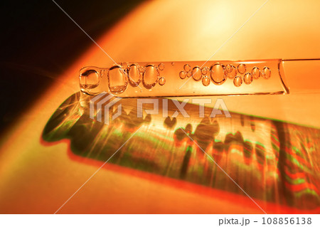 A dropper with sunscreen body serum in the orange sunset light. 108856138