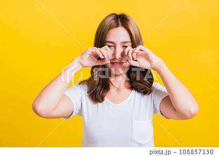 Asian Thai portrait beautiful cute young woman in depressed bad mood her cry wipe tears with fingers, studio shot isolated on yellow background with copy space 108857130