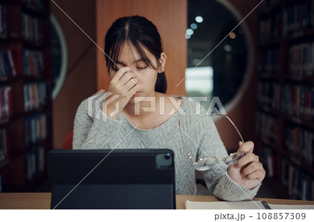 Asian student woman read books in library at university. Young girl stress tired have problem while study hard. Sadness concept 108857309