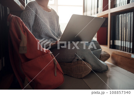 Student girl sitting on floor and using laptop, Writes notes for paper, Essay, Study for class assignment. Diverse group of Students Learning, Studying for Exams. Student girl sitting on floor and using laptop, Writes notes for paper, Essay, Study for class assignment. Diverse group of Students Learning, Studying for Exams. 108857340