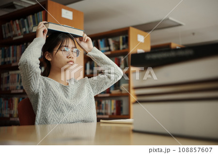 Asian student woman read books in library at university. Young girl stress tired have problem while study hard. Sadness concept 108857607
