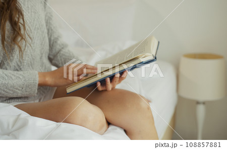Young woman reading book on bed at home. 108857881