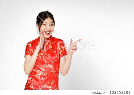 Happy Asian woman wearing traditional cheongsam qipao dress hand pointing up to copy space isolated on white background. Happy Chinese new year. Happy Asian woman wearing traditional cheongsam qipao dress hand pointing up to copy space isolated on white background. Happy Chinese new year. 108858102