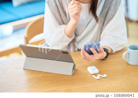 スマートフォンとタブレットPCの画面を見る女性の手元 108860041