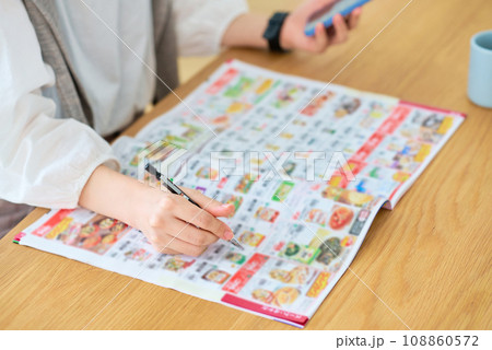 広告の冊子をチェックする女性の手元 108860572