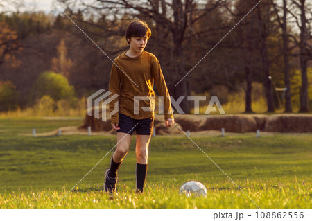 Teenage boy of 11-13 years old in sports uniform trains in summer morning on field with soccer ball. Sports and health. Teenage boy of 11-13 years old in sports uniform trains in summer morning on field with soccer ball. Sports and health. 108862556