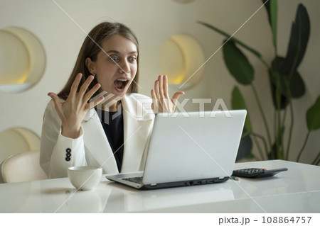 Happy excited woman at home workstation triumphing with raised hands Happy excited woman at home workstation triumphing with raised hands 108864757