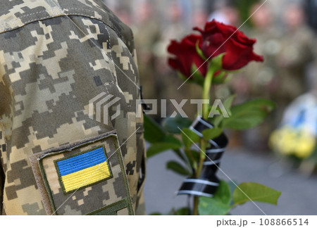 Ukrainian flag on military uniform. Soldier holds flowers A funerals of Ukrainian servicemen. 108866514