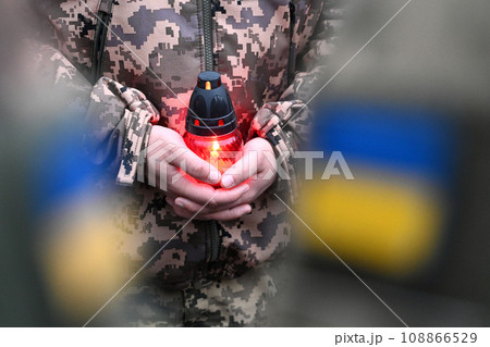 A Ukrainian seviceman holds a candle. Ukrainian flag on military uniform. Candle in hands of Soldier 108866529