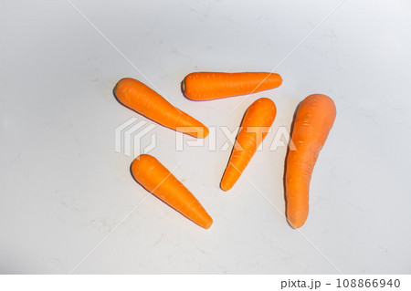 Fresh Carrot lay on white marble top table surface background with hard light and shadow on it. Fresh Carrot lay on white marble top table surface background with hard light and shadow on it. 108866940