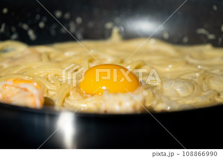 Close up macro to yolk in Creamy fried and boiled Spaghetti pasta in hot pan. Close up macro to yolk in Creamy fried and boiled Spaghetti pasta in hot pan. 108866990