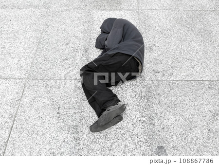 Homeless man sleeps on the ground in the city center 108867786