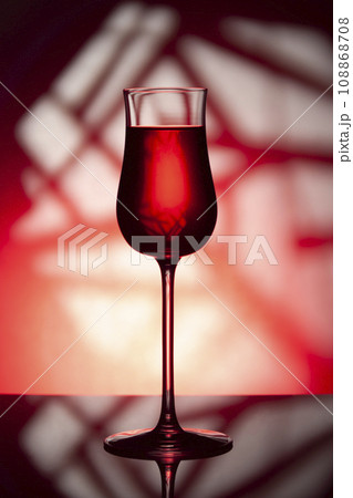 Glass of wine on a red background. 108868708