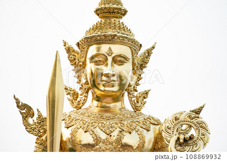 A golden graven image standing with a sword and rowel in his hand. Jada's multiple layers are placed on his head. He was standing on golden bases against a white backdrop A golden graven image standing with a sword and rowel in his hand. Jada's multiple layers are placed on his head. He was standing on golden bases against a white backdrop 108869932