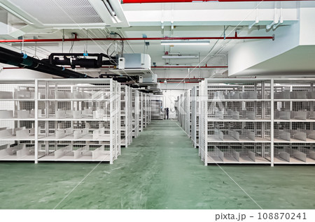 White shelves are lined up all over the area in a warehouse with a green floor. It also has an excellent security system. 108870241