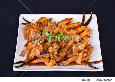 Crispy prawns in tamarind sauce in  white square dish, sprinkle with glaze and top with fried shallots and coriander. It has perfect balance of crispy, spicy, and sweet flavors. 108870262