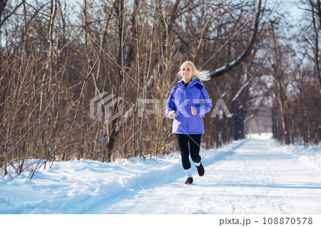 Young woman in sportswear doing exercises in snowy forest. Outdoor fitness, cardio exercises. Young woman in sportswear doing exercises in snowy forest. Outdoor fitness, cardio exercises. 108870578