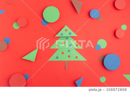 green paper Christmas tree on red, blue and brown circles and triangles concept creative idea flat 108872608
