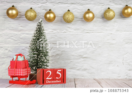 Decorative Christmas tree and red wooden perpetual calendar with date on white brick background. Decorative Christmas tree and red wooden perpetual calendar with date on white brick background. 108875343