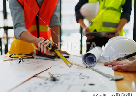 engineers discuss building on blueprint drawing, design building Project in office engineers discuss building on blueprint drawing, design building Project in office 108875682