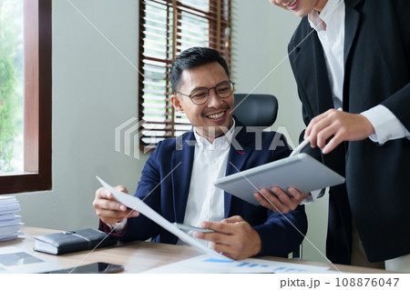 Concept of the impact of warring countries, male economists are using tablets to consult with marketing staff or accountants to adjust production and investment strategies to the current situation. 108876047