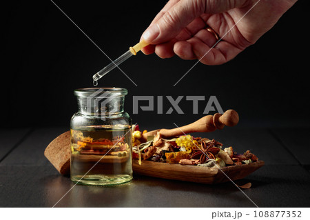 Dropping essential oil or herbal tincture into a small bottle. Dropping essential oil or herbal tincture into a small bottle. 108877352