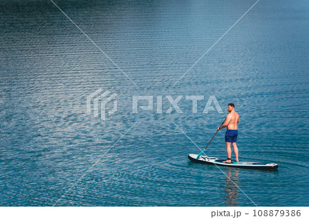 man balancing on supboard paddling 108879386